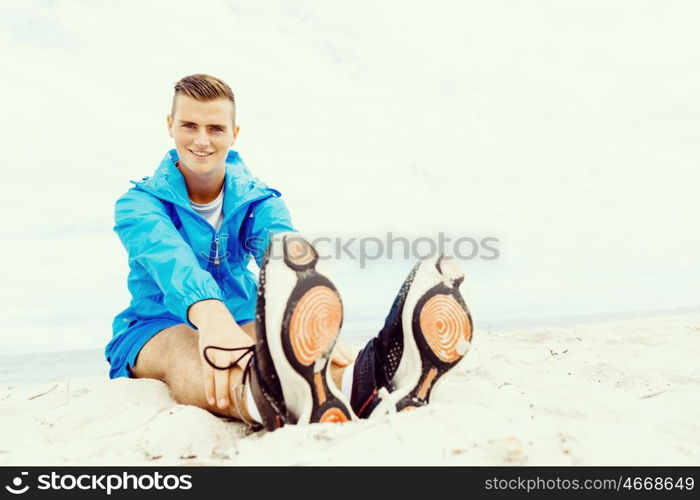 Man training on beach outside. Handsome caucasian male doing exercises on beach