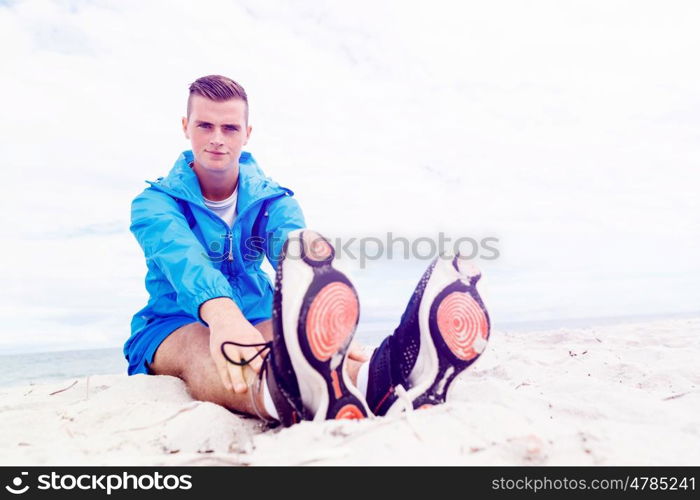 Man training on beach outside. Handsome caucasian male doing exercises on beach