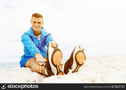 Man training on beach outside. Handsome caucasian male doing exercises on beach