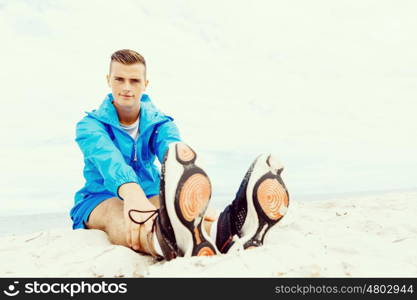 Man training on beach outside. Handsome caucasian male doing exercises on beach