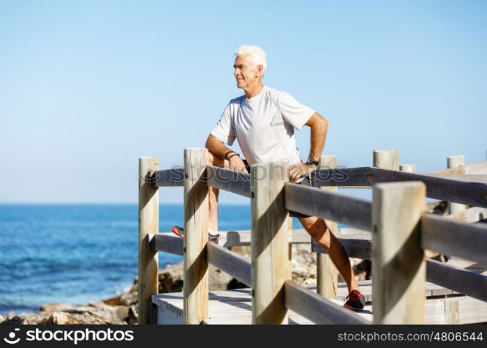 Man training on beach outside. Handsome caucasian male doing exercises on beach