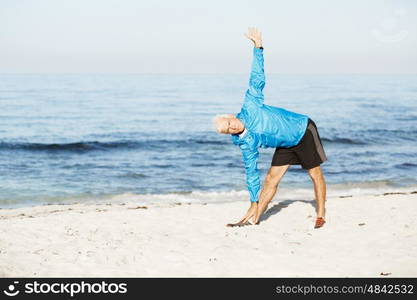 Man training on beach outside. Handsome caucasian male doing exercises on beach