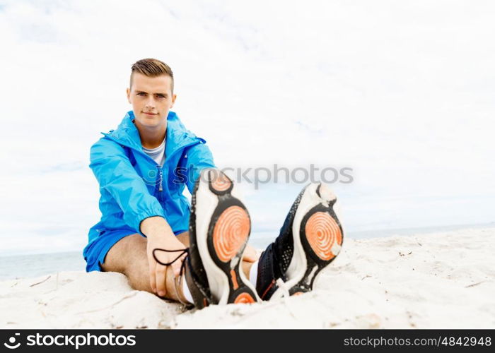 Man training on beach outside. Handsome caucasian male doing exercises on beach