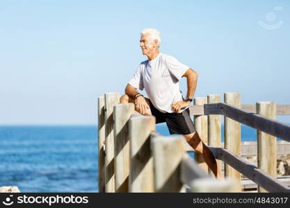 Man training on beach outside. Handsome caucasian male doing exercises on beach