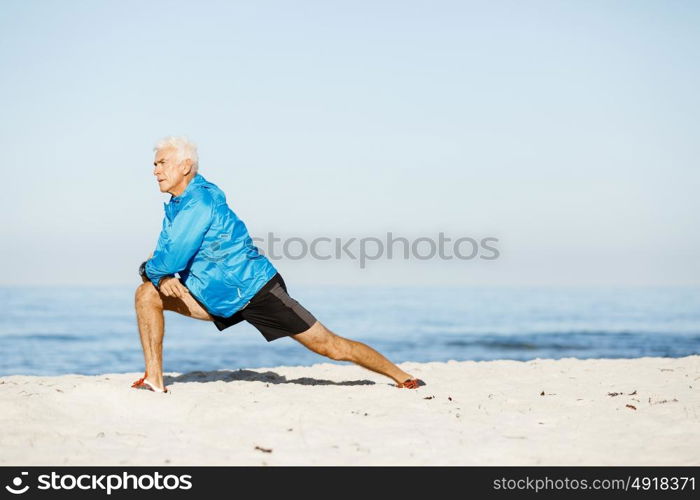 Man training on beach outside. Handsome caucasian male doing exercises on beach