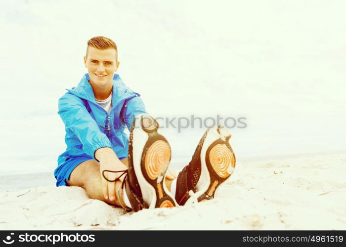 Man training on beach outside. Handsome caucasian male doing exercises on beach