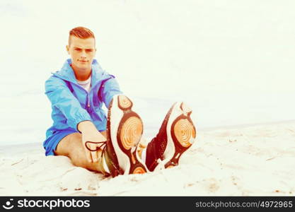 Man training on beach outside. Handsome caucasian male doing exercises on beach