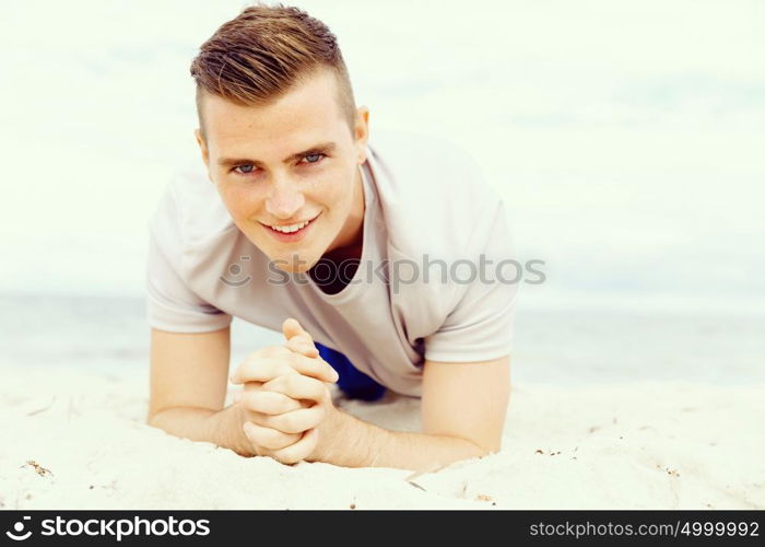 Man training on beach outside. Handsome caucasian male doing exercises on beach