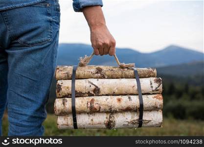 Man traveler hands holding firewood for fire in mountains. place for inscription. Man traveler hands holding firewood for fire in mountains. place for inscription.