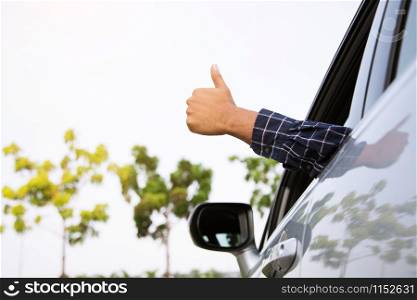 Man traveler ready to leave drive a car on the road. showing hand thumb up outdoor.