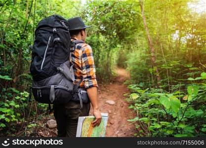 man traveler with backpack and map in the natural forest