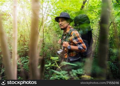 man traveler with backpack looking to the side walking in the natural forest