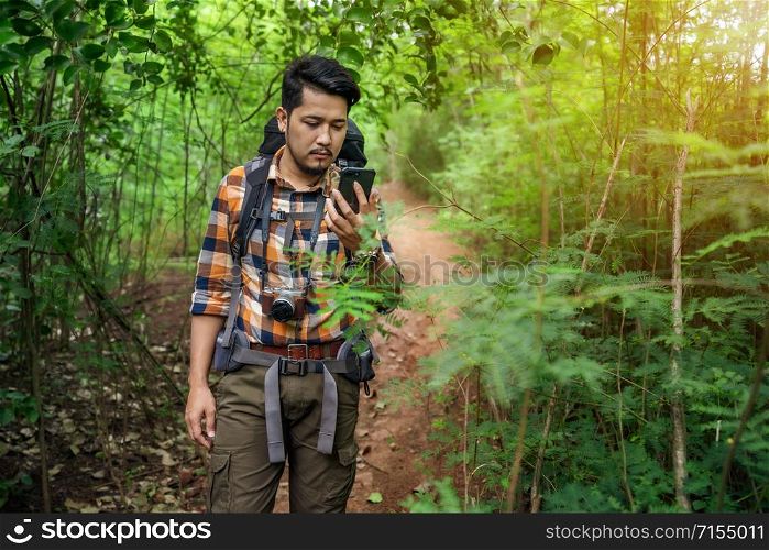 man traveler with backpack using smartphone in the natural forest