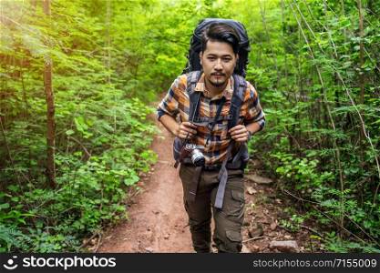 man traveler with backpack walking and looking in the natural forest