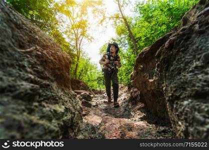 man traveler with backpack walking and looking in the natural forest