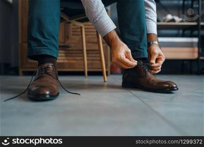 Man tries on repaired shoes, footwear repair service. Craftsman skill, shoemaking workshop, master works with boots, cobbler shop