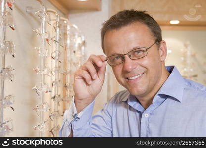 Man trying on eyeglasses at optometrists smiling