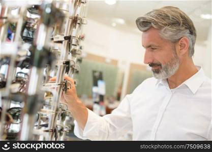 man trying on eyeglasses at optometrists smiling