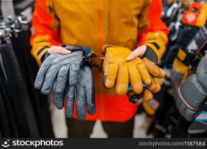 Man trying on gloves for ski or snowboarding, sports shop. Winter season extreme lifestyle, active leisure store, male customer with protect equipment. Man trying on gloves for ski or snowboarding