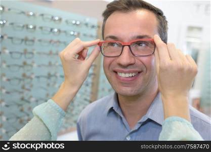 man trying on new glasses at opticians
