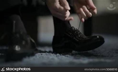 Man tying patent leather shoes. Formal and festive dressing.