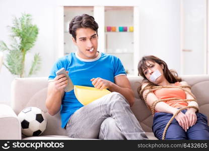 Man tying up his wife to watch sports football