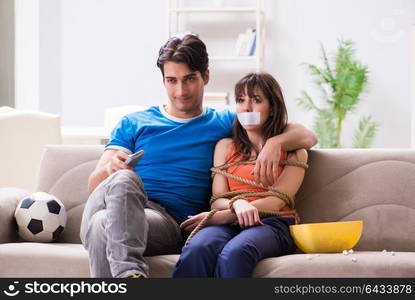 Man tying up his wife to watch sports football