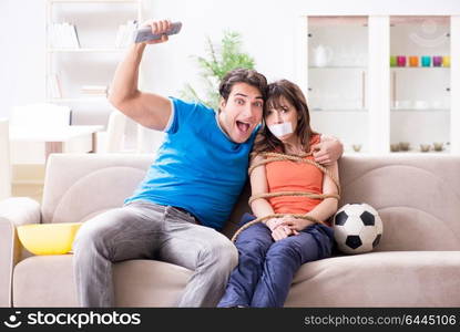 Man tying up his wife to watch sports football