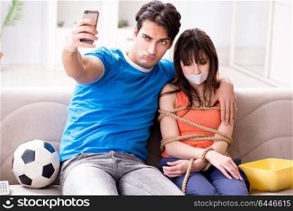 Man tying up his wife to watch sports football