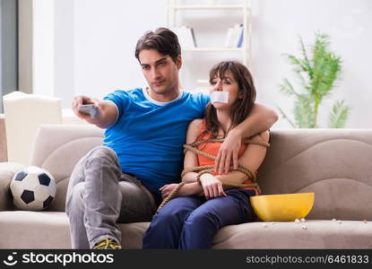 Man tying up his wife to watch sports football