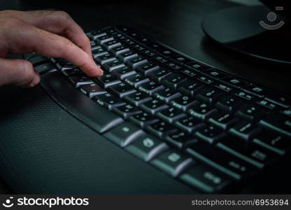 Man typing on a keyboard with letters in Hebrew and English - Wireless keyboard - Dark atmosphere