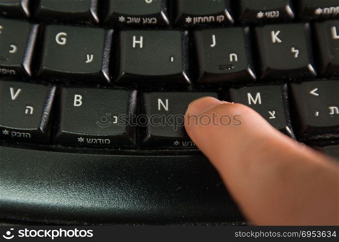 Man typing on a Wireless keyboard with letters in Hebrew and English - Press the New button - Top View