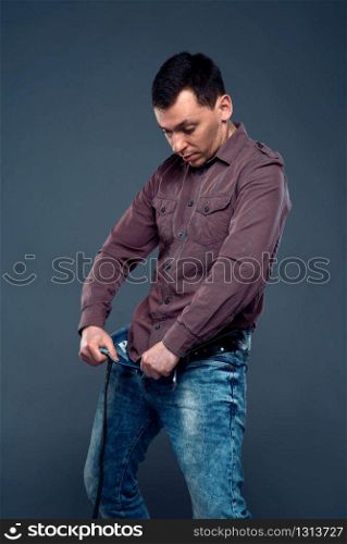 Man unbuttoned pants and looking at his penis. No problem with prostate, potency concept. No troubles with inpotence