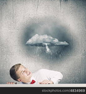 Man under rain. Young man looking above at raining cloud