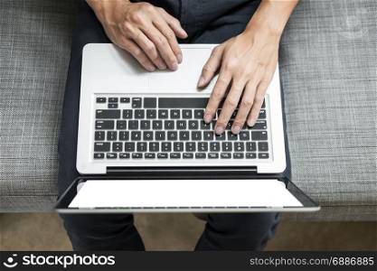 Man uses laptop on sofa in his home. High angle view, Work at home concept.