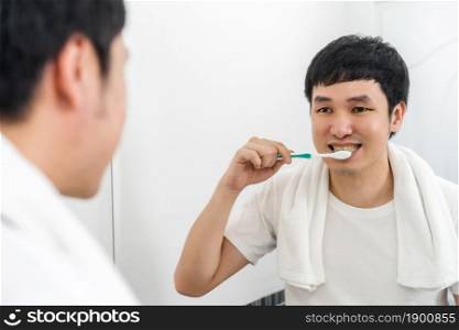 man ushing toothbrush to brushing teeth in the bathroom mirror