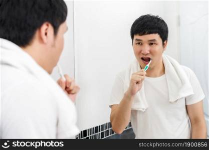 man ushing toothbrush to brushing teeth in the bathroom mirror