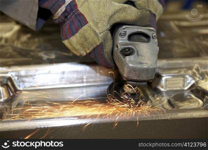 man using a angle grinder on metal surface with sparks