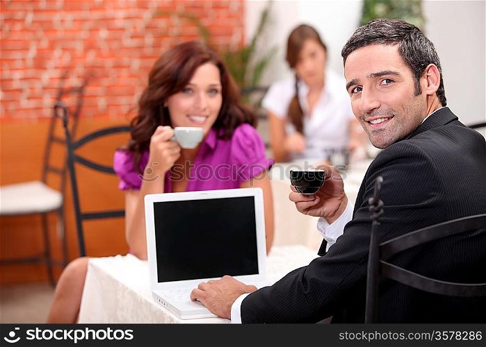 Man using a laptop computer in a cafe with a blank screen for your image