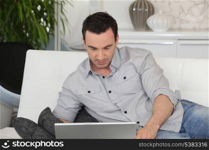 Man using a laptop on a sofa