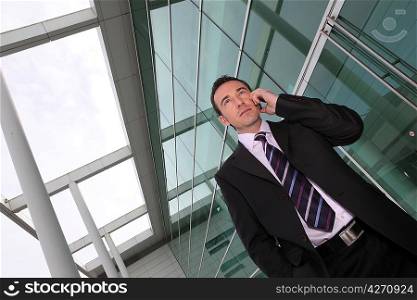 Man using a mobile outside a glass fronted building