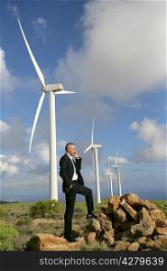 Man using a mobile phone next to wind turbines
