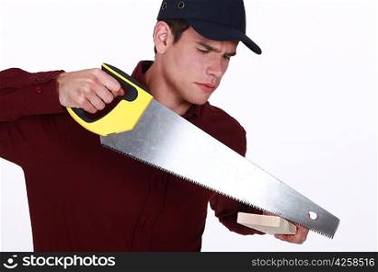 Man using a saw to cut a wooden plank