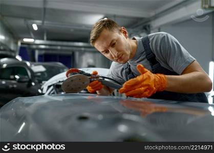 Man using angle grinder to cut off excess rusty metal from car body. Auto renovation service. Man using grinder to remove car rust