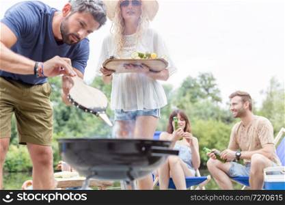 Man using bellows for preparing food in barbecue grill with friends on pier
