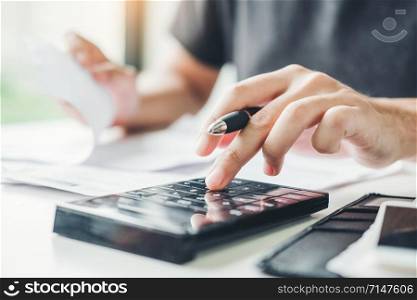 Man using calculator Accounting Calculating Cost Economic bills with money stack step growing growth saving money in home , finance concept