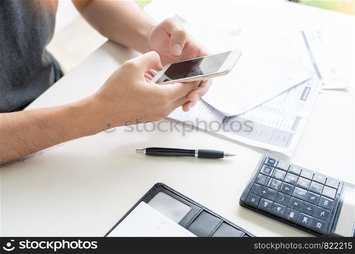 Man using calculator and calculate bills receipt in home expenses payments costs with paper note, financial account management and payment or saving concept