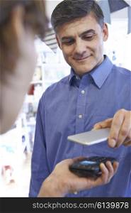 Man Using Contactless Payment App On Mobile Phone In Store