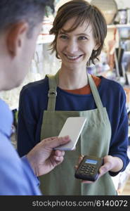 Man Using Contactless Payment App On Mobile Phone In Store