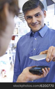 Man Using Contactless Payment App On Mobile Phone In Store